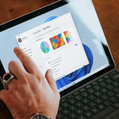 A hand tapping a dashboard of charts on a tablet with a keyboard cover.