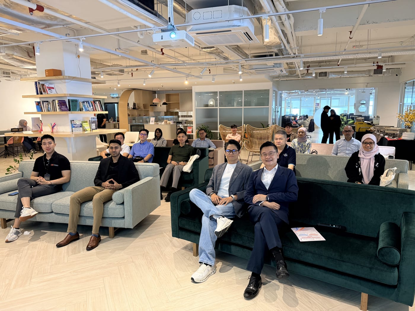 Workshop attendees seated on sofas in a bright open-plan event space, smiling toward the camera.